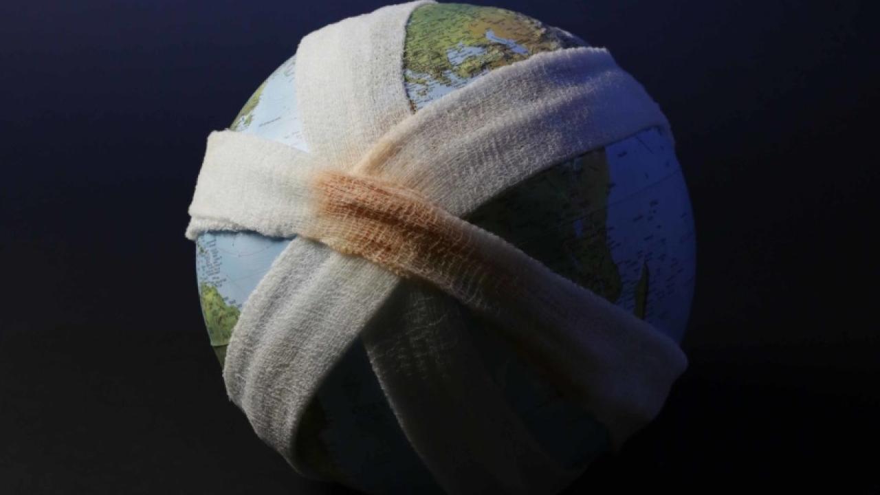 A globe wrapped in bandages, with a blemished spot "bleeding" underneath.