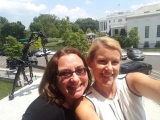 Two women smile in a selfie in front of the White House.